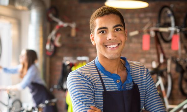Black young man standing in bike shop with arms crossed